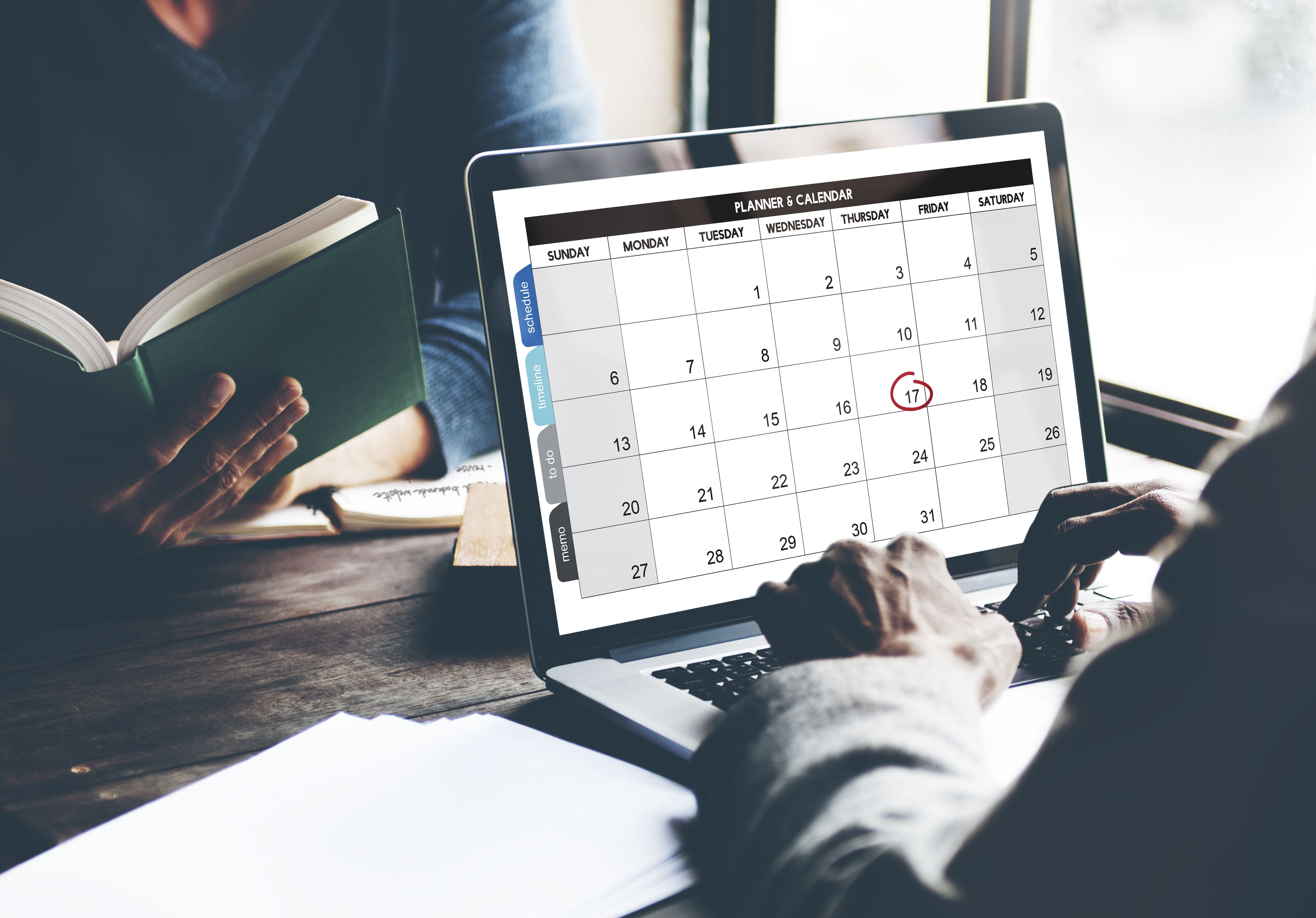 Employee updating work schedule on digital calendar — tailored software solution for SME 				timesheet and attendance tracking.