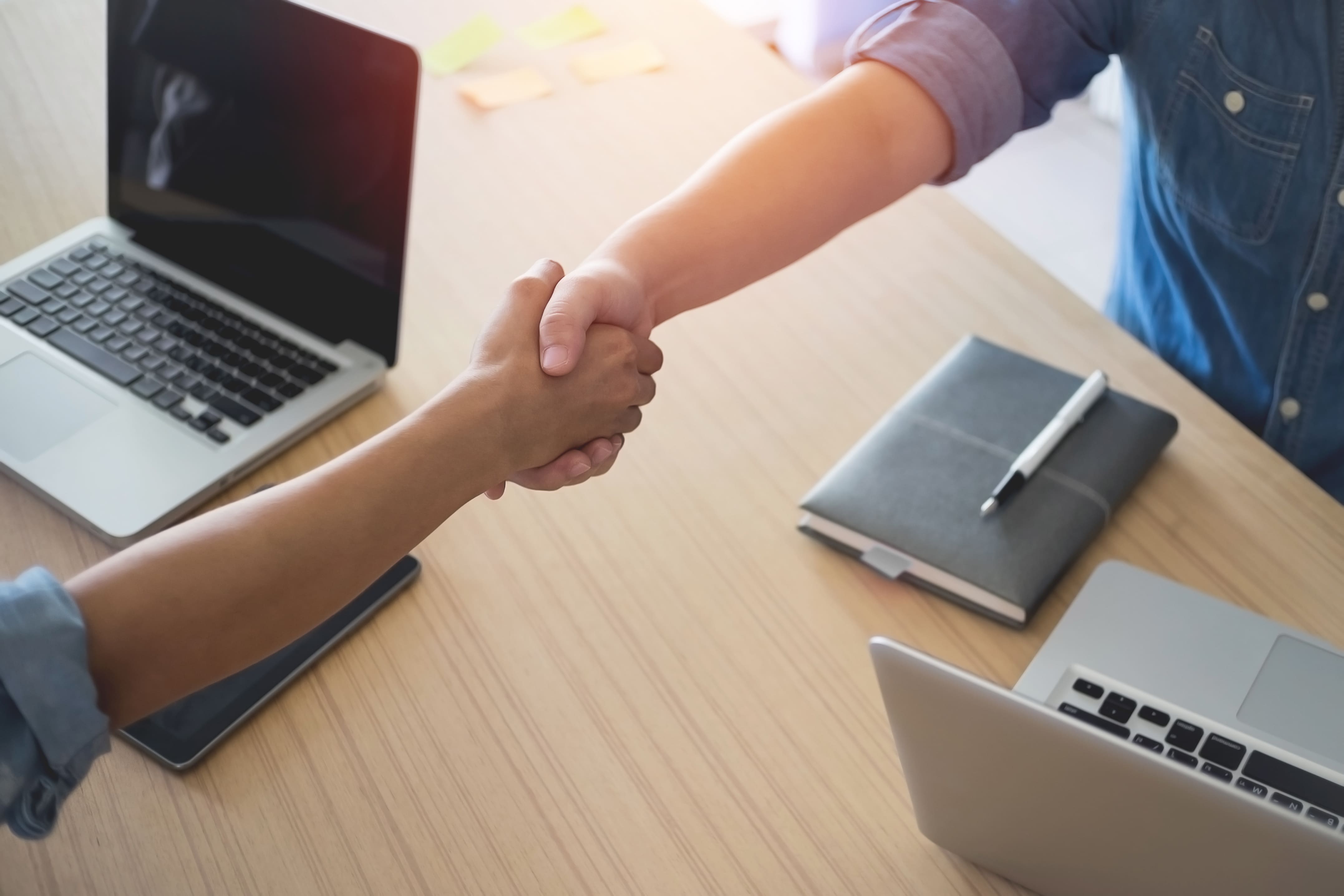 Handshake between team members — custom business solution for streamlining customer 					onboarding workflows.