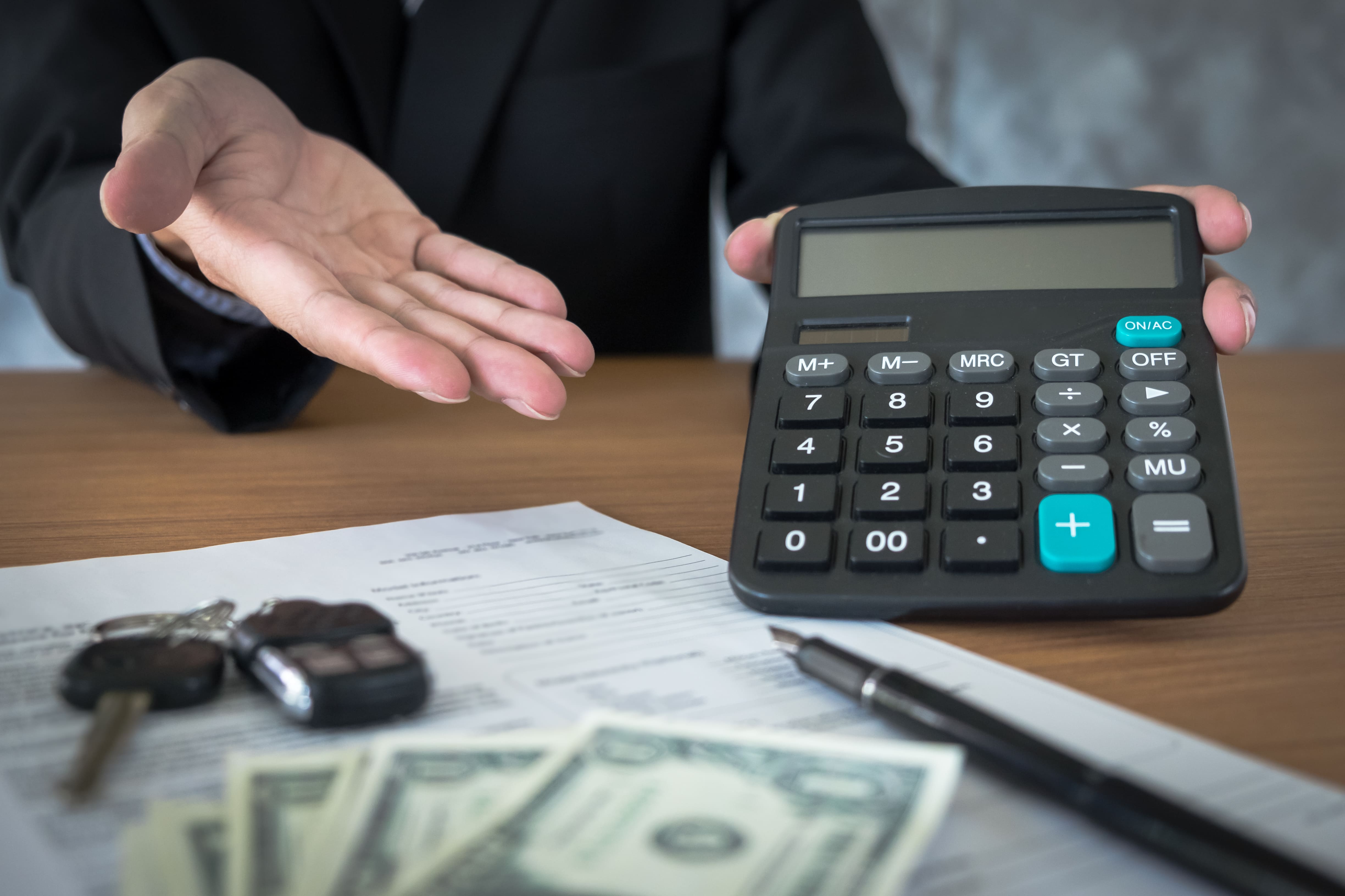 Business professional showing calculator with cash, documents, and car keys — custom 					software for managing employee expense claims.