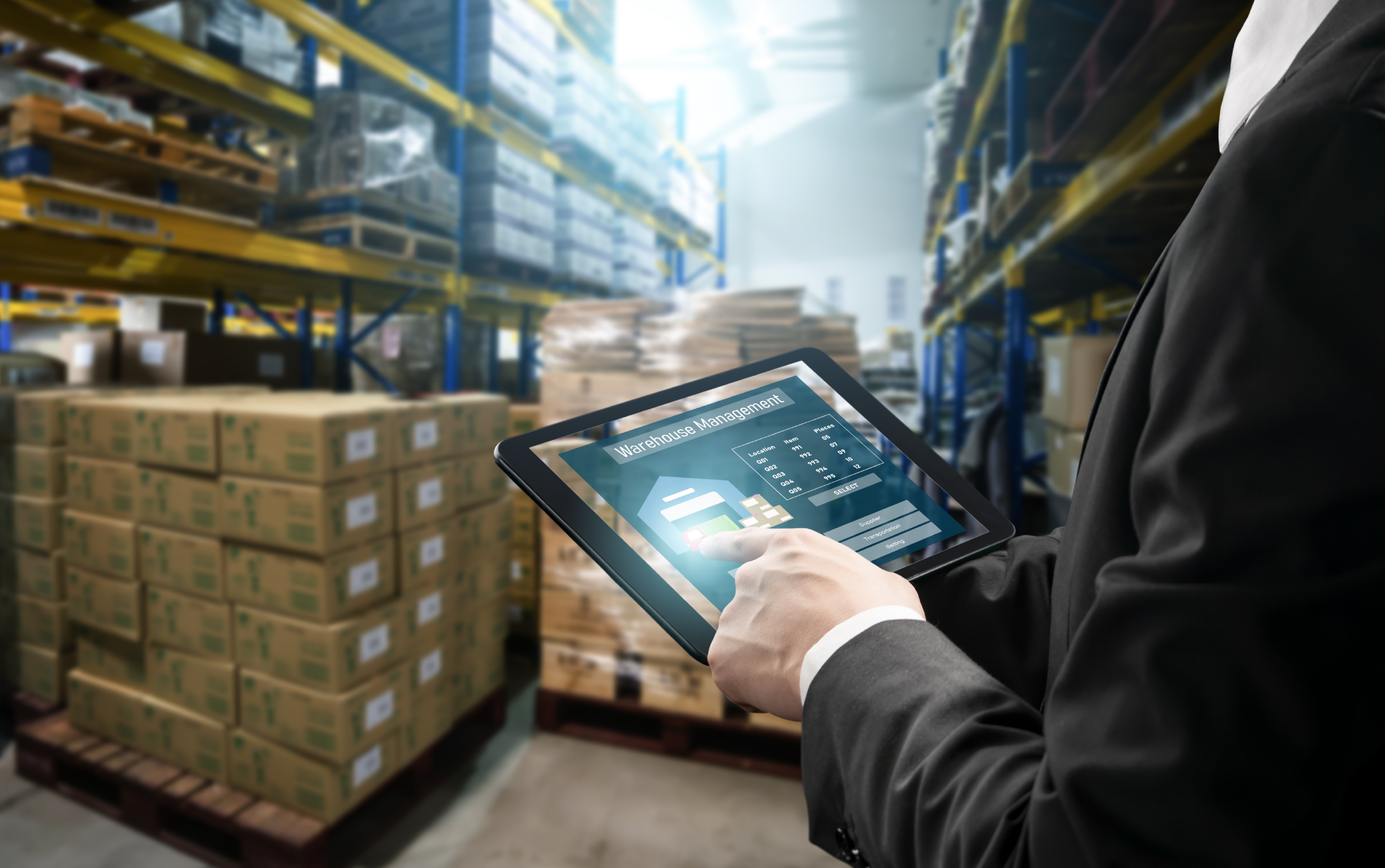 Person using a tablet to manage stock in a warehouse — custom business solution for 				real-time inventory tracking.
