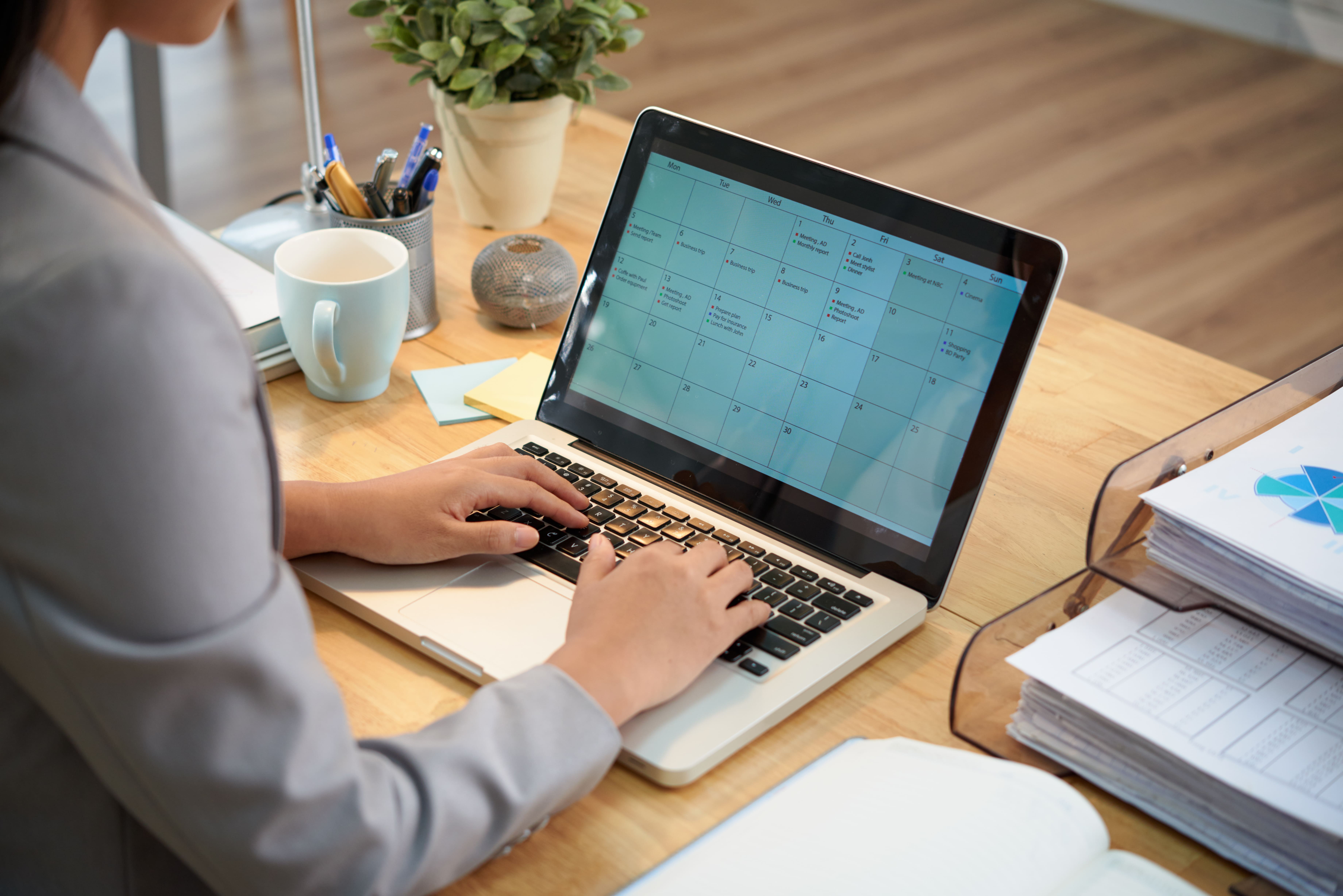 HR professional managing leave calendar on laptop — custom SME solution for streamlining 				employee leave management.
